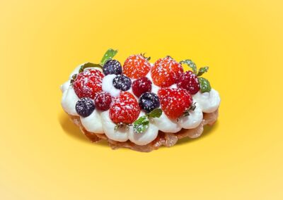 Delicious boba dessert with fresh berries and whipped cream on a yellow background.